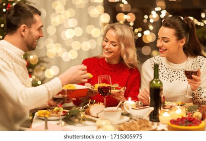 holidays and celebration concept - happy friends having christmas dinner at home, eating and drinking - Powered by Shutterstock