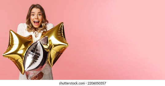 Holidays, celebration and women concept. Happy charming and surprised girl being congratulated with birthday, holding star-shaped balloons and smiling joyfully camera, pink background - Powered by Shutterstock