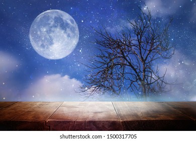 Holidays Halloween concept. Empty rustic table in front of scary and misty night sky and full moon background. Ready for product display montage
