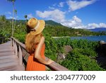 Holidays in Ilhabela, Brazil. Young female tourist enjoying view from trail of tropical beach Praia Pedra do Sino, Ilhabela, Brazil.