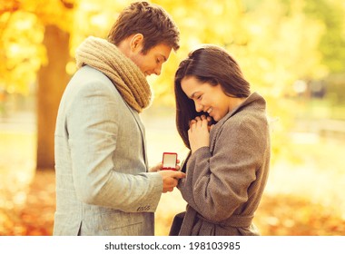 holidays, love, couple, relationship and dating concept - romantic man proposing to a woman in the autumn park - Powered by Shutterstock