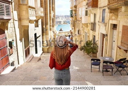Holidays in Malta. Back view of traveler woman descends stairs in the historic city of Valletta, UNESCO World Heritage, Malta.