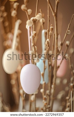 Holidays and object concept. Close up of pussy willow branches decorated by easter eggs over bokeh lights. Vertical photo