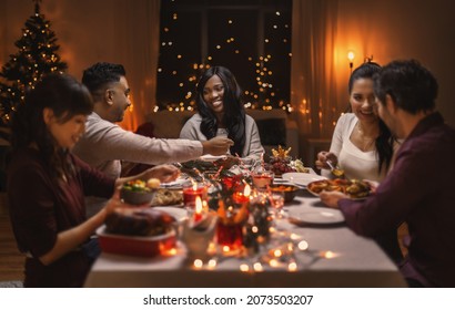holidays, party and celebration concept - multiethnic group of happy friends having christmas dinner at home - Powered by Shutterstock