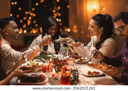holidays, party and celebration concept - multiethnic group of happy friends having christmas dinner at home