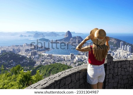 Holidays in Rio de Janeiro. Rear view of tourist woman enjoying sight of famous Guanabara Bay with Sugarloaf Mountain in Rio de Janeiro, UNESCO World Heritage, Brazil.
