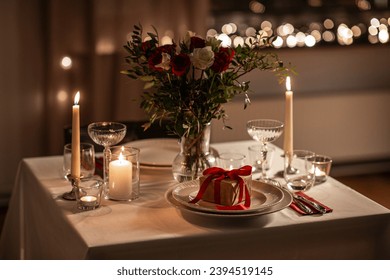 holidays, romantic date and celebration concept - close up of festive table serving for two with gift box, flowers in vase and candles burning at home on valentine's day at home - Powered by Shutterstock