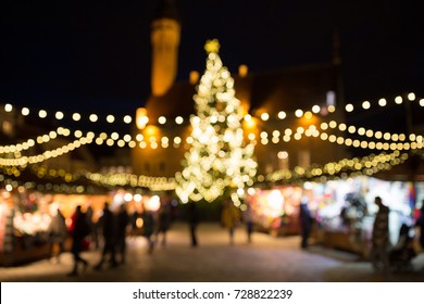 holidays, sale and retail concept - evening christmas market at old town hall square in tallinn bokeh