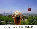 Holidays in Santiago de Chile. Rear view of beautiful fashion girl enjoying view of cable cars in Santiago Metropolitan Park, Chile. Summer vacation in South America.