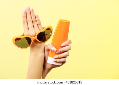 Holidays Summer Fashion Eyes Protection And Skin Care Concept. Woman Holding In Hand Heart Shaped Sunglasses Sunscreen Lotion, Yellow Background