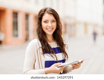 holidays and tourism concept - beautiful girl looking into tourist book in the city - Powered by Shutterstock