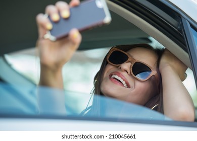 Holidays And Tourism Concept - Smiling Teenage Girl Taking Selfie Picture With Smartphone Camera Outdoors In Car