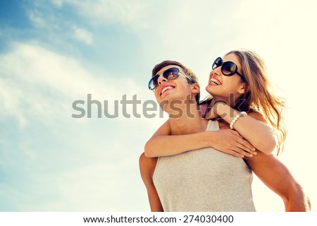 holidays, vacation, love and friendship concept - smiling couple having fun over sky background