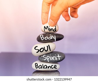 Holistic Health Concept Of Zen Stones With Female Hand  On Black And White Background. Text Mind Body Soul Spirit Balance. 