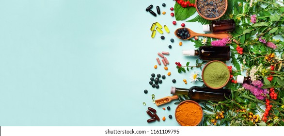 Holistic medicine approach. Healthy food eating, dietary supplements, healing herbs and flowers. Turmeric, dried lavender, spirulina powder in wooden bowls, fresh berries, omega acid capsules.