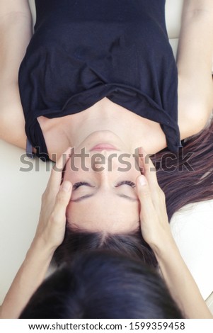 holistic therapist performs Cranial sacral therapy to a young woman - girl receives outdoor shiatsu treatments