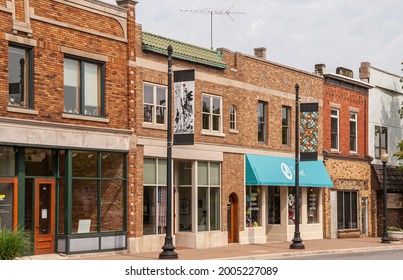 Holland, MI, USA - June 8, 2008: Historic District. Row Of Small Red And Brown Brick Facades Of Stores With Couple Of Colorful Artsy Street Banners In Front. Gray Sky And TV Antenna