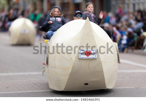 Holland, Michigan, USA - May 11, 2019: Tulip Time\
Parade, Man driving a cart in shape of a wooden clog, with his\
children, during the\
parade