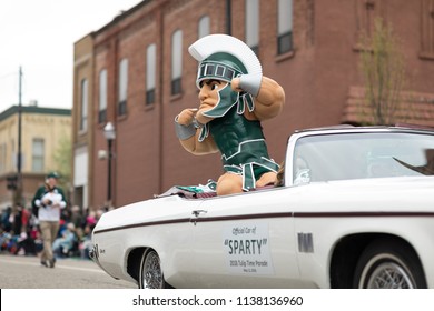 Holland, Michigan, USA - May 12, 2018 Sparty, mascot from Michigan State University rides a classic car down the road, at the Muziek Parade, during the Tulip Time Festival