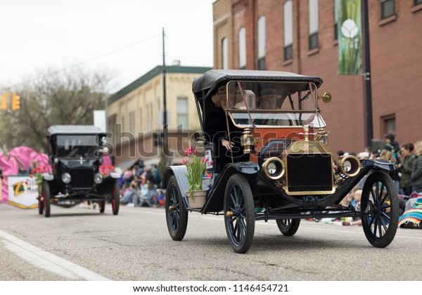 Holland,\
Michigan, USA - May 12, 2018 Ford Model T, with tulip flowers,\
driven by men wearing retro clothing, drive down the road at the\
Muziek Parade, during the Tulip Time\
Festival