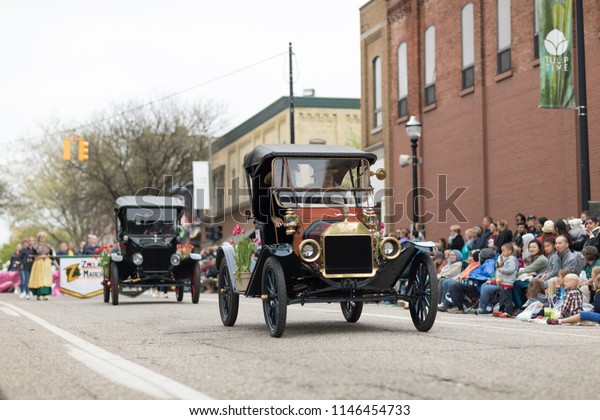 Holland,\
Michigan, USA - May 12, 2018 Ford Model T, with tulip flowers,\
driven by men wearing retro clothing, drive down the road at the\
Muziek Parade, during the Tulip Time\
Festival