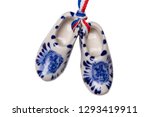 Holland wooden clogs. A pair of traditional dutch porcelain shoes with a ribbon flag isolated on a white background. Souvenir from Amsterdam. Macro.