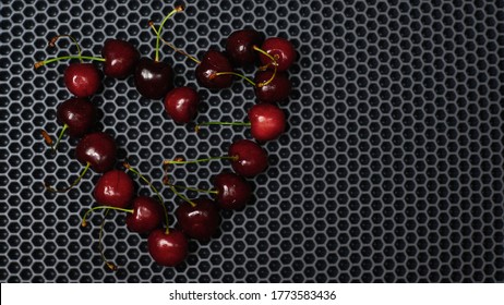 hollow heart of red cherries close up from above against a dark background