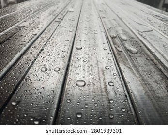 hollow structural steel sections (rectangular or square steel tubes) .The surface is covered in beads of water or condensation, showing high surface tension (often seen on clean metal, lightly oiled surfaces, or materials left outdoors in the rain).