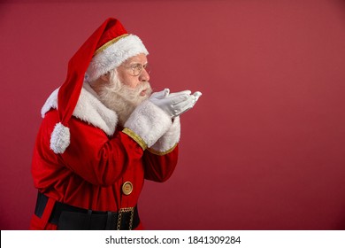 Holly jolly Xmas festive occasion Noel! Christmastime traditions! Santa in headwear, costume, white gloves expresses winter wish, surprise, fantasy, blizzard, snow, snowflakes, air kiss, blowing. - Powered by Shutterstock
