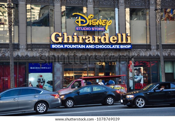 Hollywood, California - January 12, 2018: Slow\
traffic in front of Disney Studio Store and Ghirardelli soda\
fountain and chocolate\
shop.