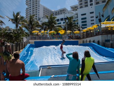 Hollywood, Florida - April 19, 2018: Young Man Showing Off By  Doing Handstand On Surfboard At Artificial Wave Pool At Margaritaville Resort In Hollywood, Florida