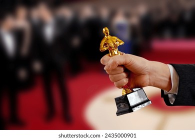 Hollywood Golden award statue in his hand at an awards ceremony background. Success and victory concept.