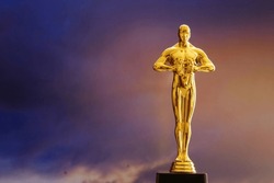 Hollywood Golden Oscar Academy Award Statue On Sky Background With Copy Space. Success And Victory Concept.