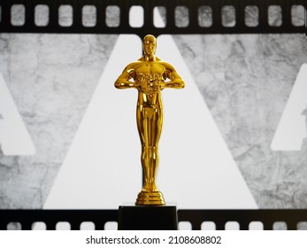 Hollywood Golden Oscar Academy award statue on old movie film background with copy space. Success and victory concept.