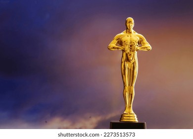 Hollywood Golden Oscar Academy award statue on sky background with copy space. Success and victory concept.