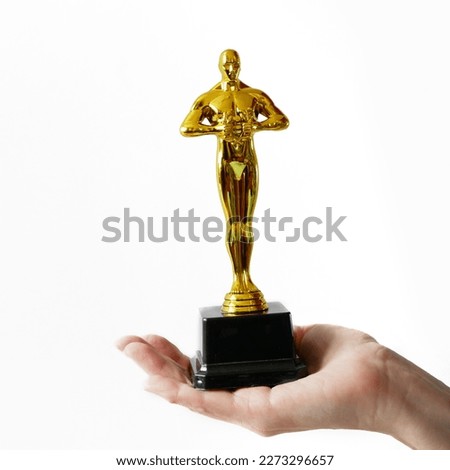 Hollywood Golden Oscar Academy award statue in hand isolated on white background. Success and victory concept.
