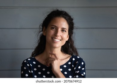 Hollywood smile. Headshot portrait of cheerful young latin woman brunette with long curly hair posing by wooden wall. Smiling millennial hispanic female coquette squinting eyes touching neck flirting