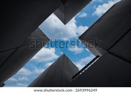 Holocaust Memorial abstract view - Dramatic low-angle abstract view looking up through the massive concrete stelae of the Holocaust Memorial in Berlin to the blue sky above.