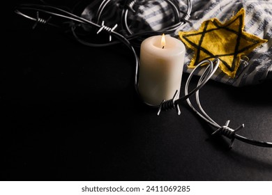 Holocaust memory day. Arbed wire and burning candle on black background