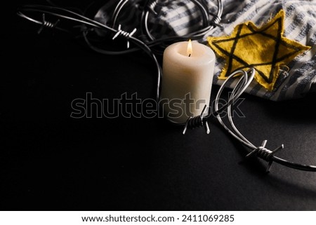 Holocaust memory day. Arbed wire and burning candle on black background