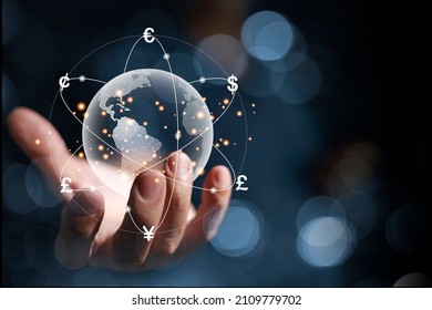 A hologram of a globe in hands of a businessman. And there are virtual lines of currency flows such as yen, yuan, dollars, pounds, euros, revolving around the world. global currency exchange concept - Shutterstock ID 2109779702