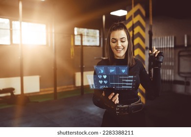 Hologram of health, organism and training statistics. A woman using a hologram at the gym to check her training stats. Modern training concept