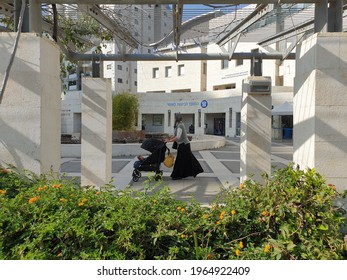 HOLON, ISRAEL. April 25, 2021. Jewish religious woman with a little child walking past the Bituach Leumi office (Israel national social security institute). Israel social service concept image.