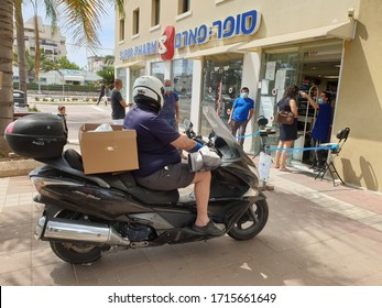 HOLON, ISRAEL. April 27, 2020. Pharmacy staff worker measuring temperature of the visitors at the shop's entrance. COVID-19 coronavirus measures.
