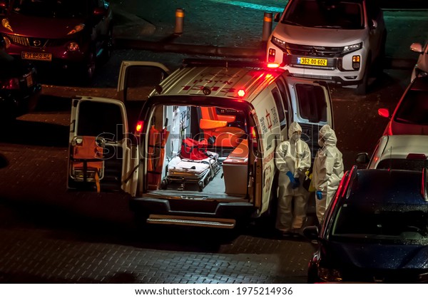 HOLON, ISRAEL. February 4, 2021. Two medical\
ambulance paramedic team staff hospitalizing a patient with\
positive COVID-19 test. Medics wearing personal protective\
equipment against\
coronavirus