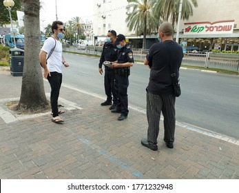 HOLON, ISRAEL. July 6, 2020. Israeli Police Officers Giving Out Fine Reports To Israelis Without Protective Face Masks Or Those Who Don't Wear Them Right. Coronavirus Pandemic Second Wave Concept