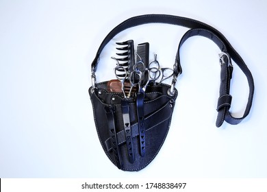 Holster For The Hairdresser. Barber Tool Bag Isolated On White Background. Black Bag With Pockets, A Plastic Comb, Metal Scissors, Black Hairpins And Combs