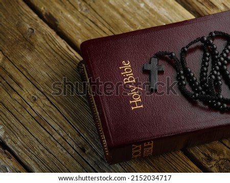 The Holy Bible book with a rosary and a cross lies on a wooden table. Low angle view.Prayer, symbols of spirituality, christianity, catholicism. There are no people in the photo.