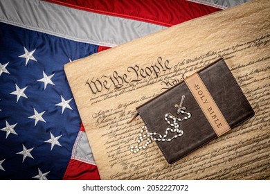 A holy bible and crucifix rest atop the United States Constitution and American flag, which is emblematic of freedom of religion without persecution.