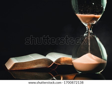 Holy Bible and hourglass representing signs of a coming apocalypse to the world.